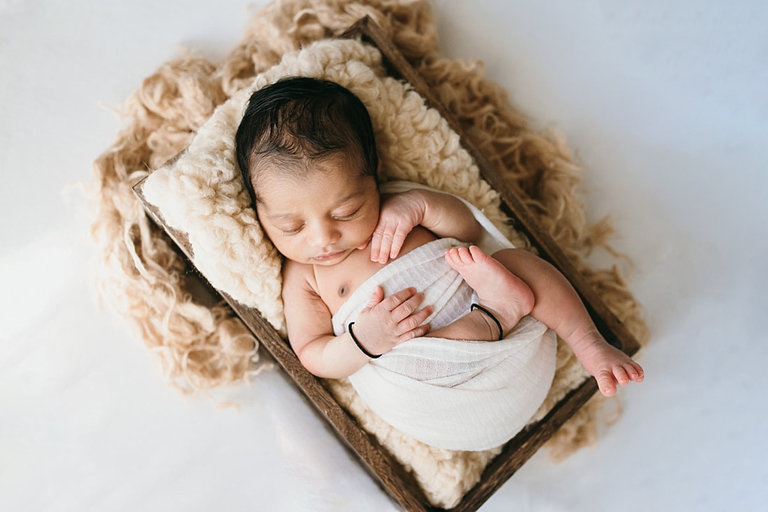 newborn wrapped in cream colored swaddle for newborn photos in memphis