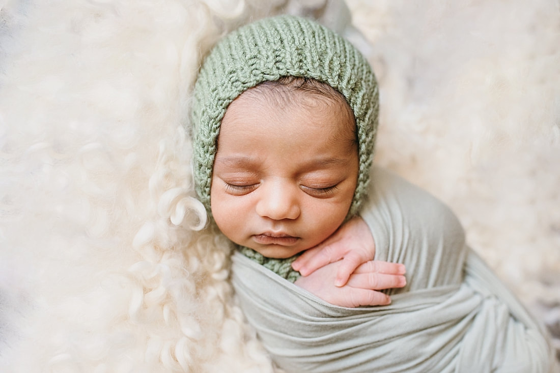 close up of baby boy's face wearing knit green bonnet during newborn photo session in memphis