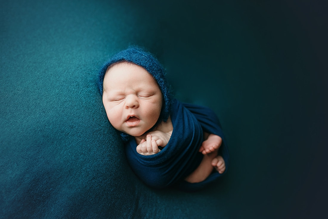 Newborn baby boy swaddled in blue blanket for newborn portrait in Memphis, TN