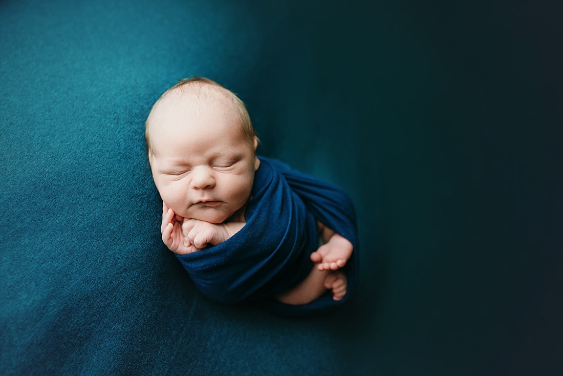 Newborn baby boy swaddled in blue blanket for newborn portrait in Memphis, TN