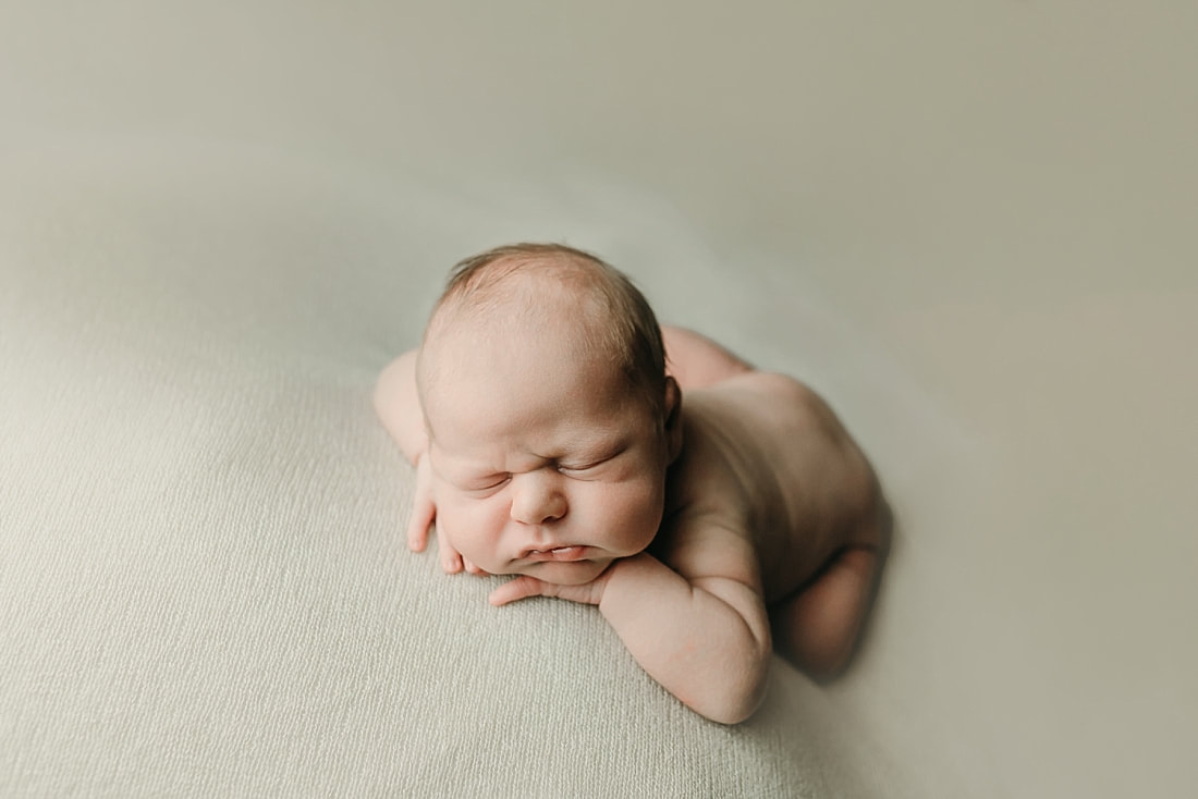 newborn baby boy posed with head in hands on tan blanket in Memphis, TN