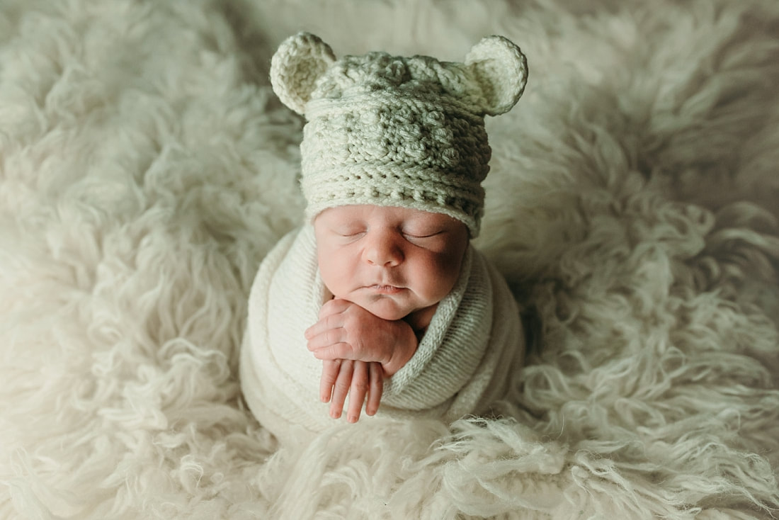 newborn baby wrapped in ivory blanket wearing teddy bear hat for newborn portraits in Memphis, TN