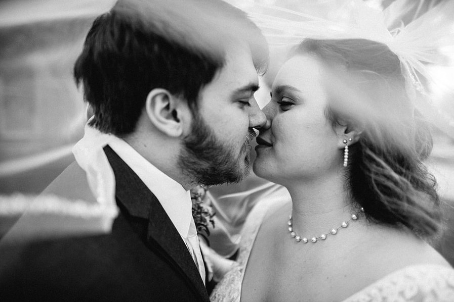 black and white wedding photo of bride and groom kissing under wedding veil in Corinth MS