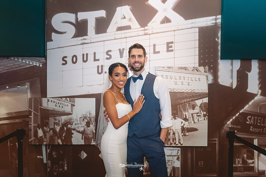 Bride and groom stopping for a quick photo in front of the vintage photos of Stax at the Stax Museum