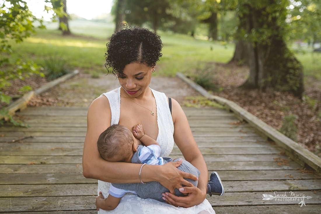 Mother breastfeeding her baby on a walking bridge in the woods at Shelby Farms Park