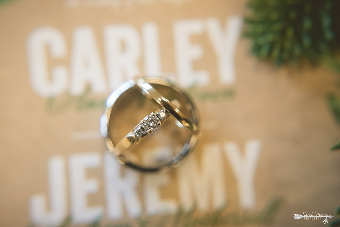 close up of wedding rings with the bride and groom's names in the background