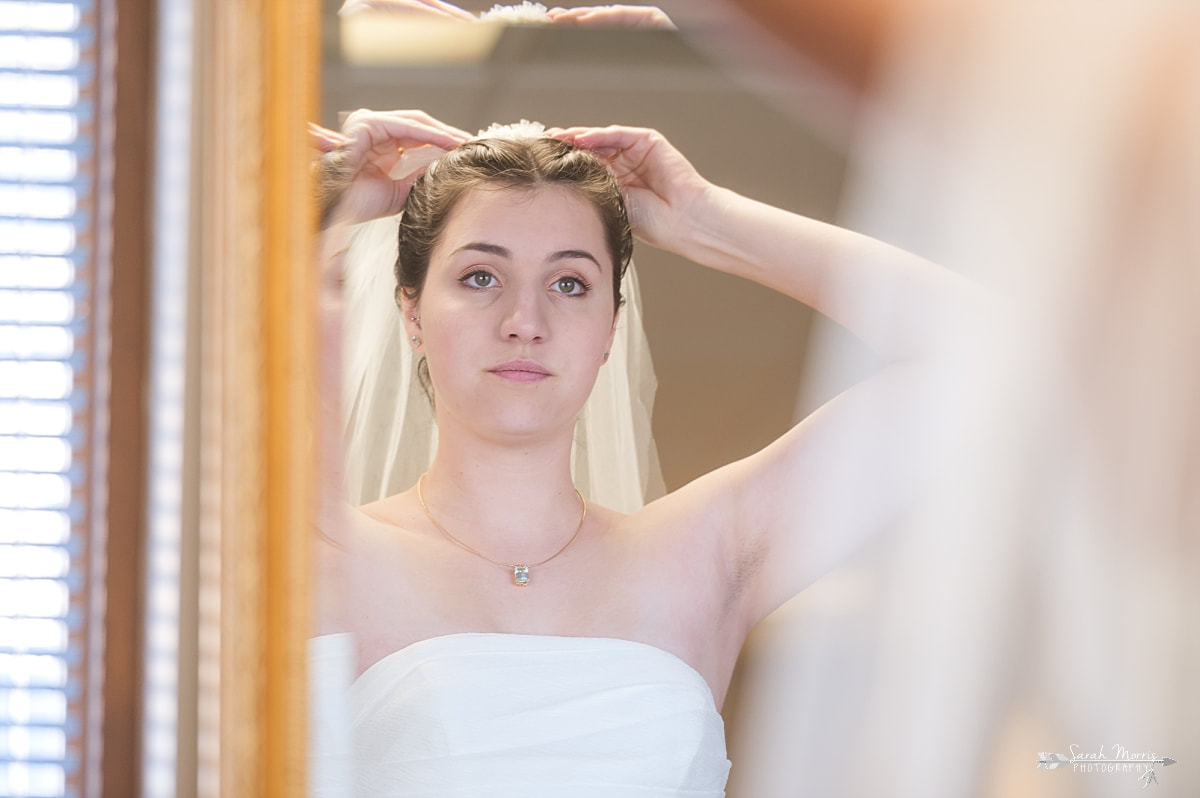 Bride adjusting her wedding veil in the mirror at St. Francis of Assisi Catholic Church