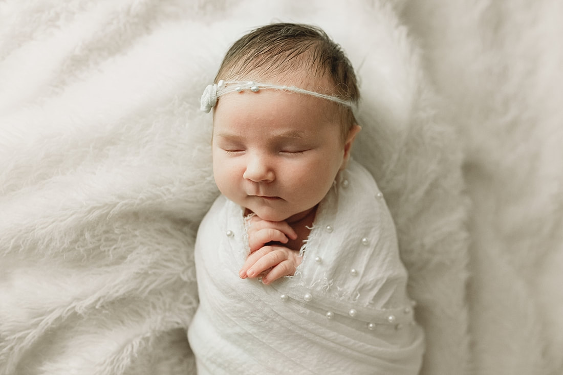baby girl swaddled in a white blanket at newborn session in memphis, tn