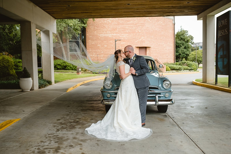 wedding photos of bride and groom kissing in front of an antique plymouth car with wedding veil floating in the wind + Memphis, TN wedding