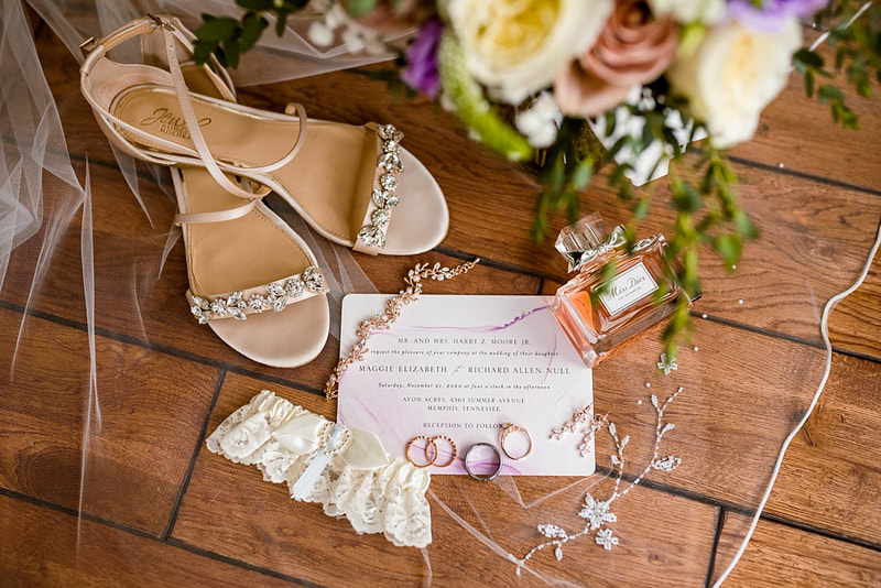 Flat lay of Bridal details: wedding shoes, wedding invitation, bride's perfume, wedding garter, bride's jewelry and bouquet at Avon Acres