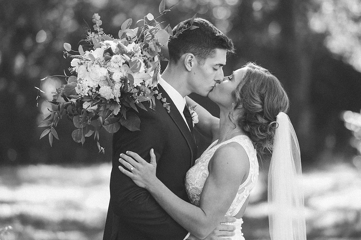 black and white portrait of bride and groom kissing