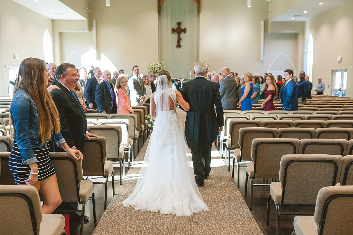 father walking his daughter down the aisle at st patrick pres church in collierville, tn