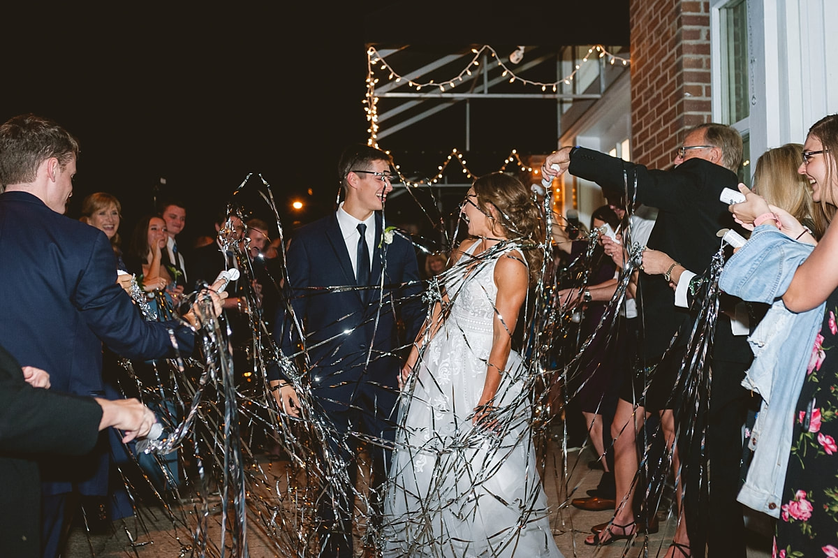 bride and groom exiting their wedding reception as wedding guests shoot confetti at them at the robinson gallery downtown memphis