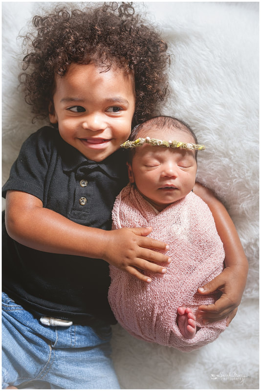 newborn photos with toddler sibling on white fur