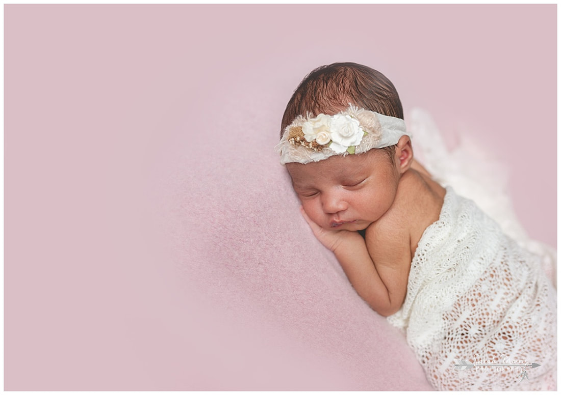 newborn photos of baby girl on pink blanket wearing flower headband