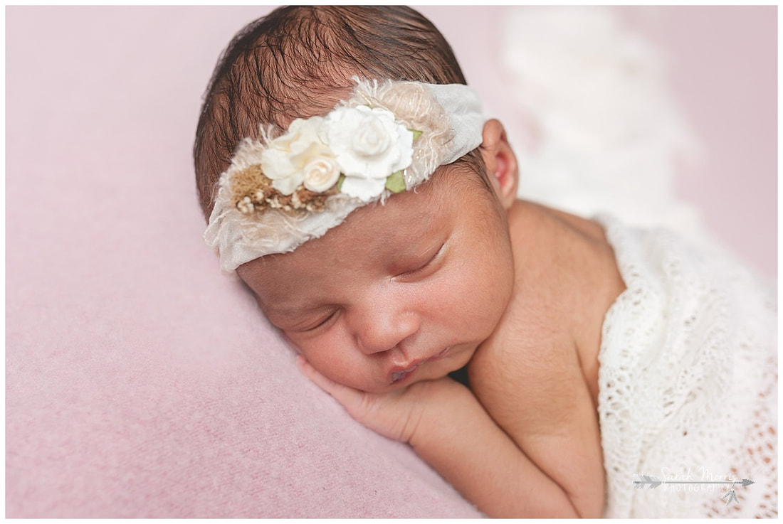 newborn photos of baby girl on pink blanket wearing flower headband