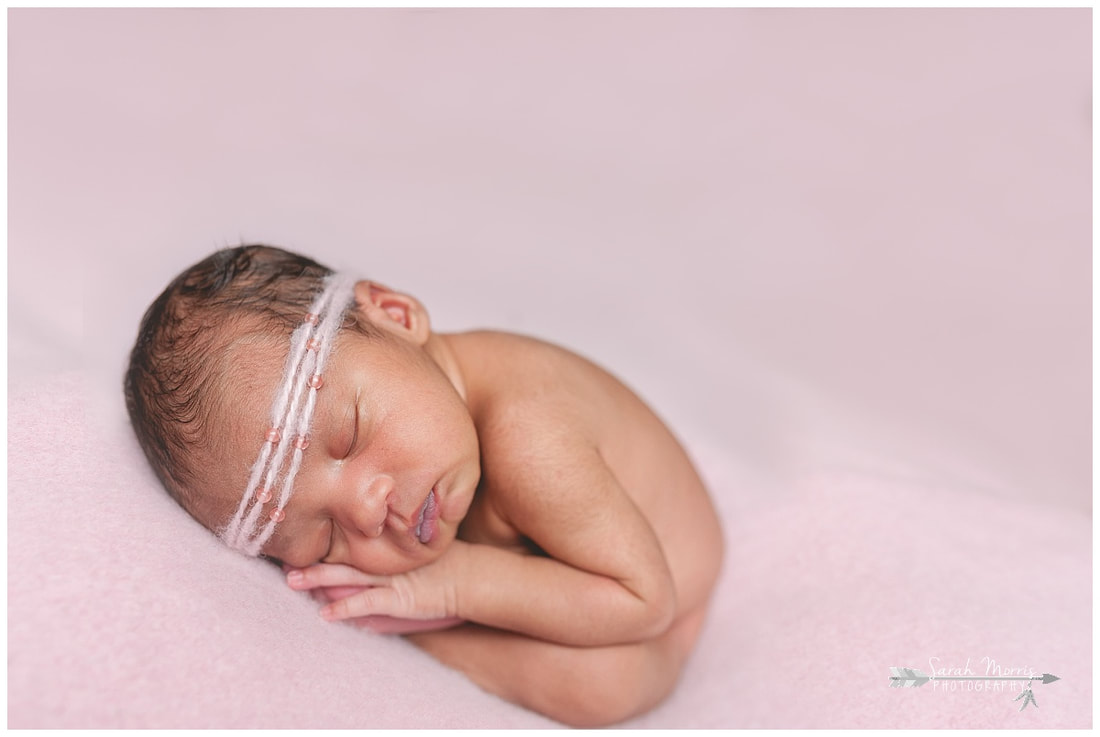 newborn photos of baby girl on pink blanket wearing pink headband