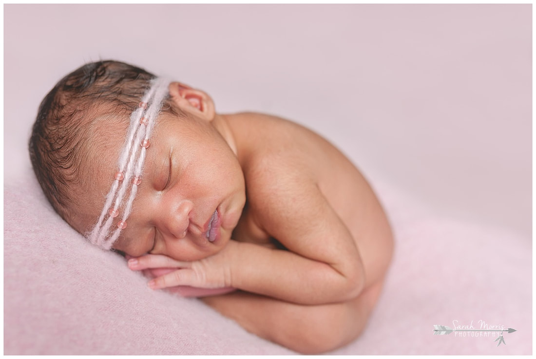 newborn photos of baby girl on pink blanket wearing pink headband