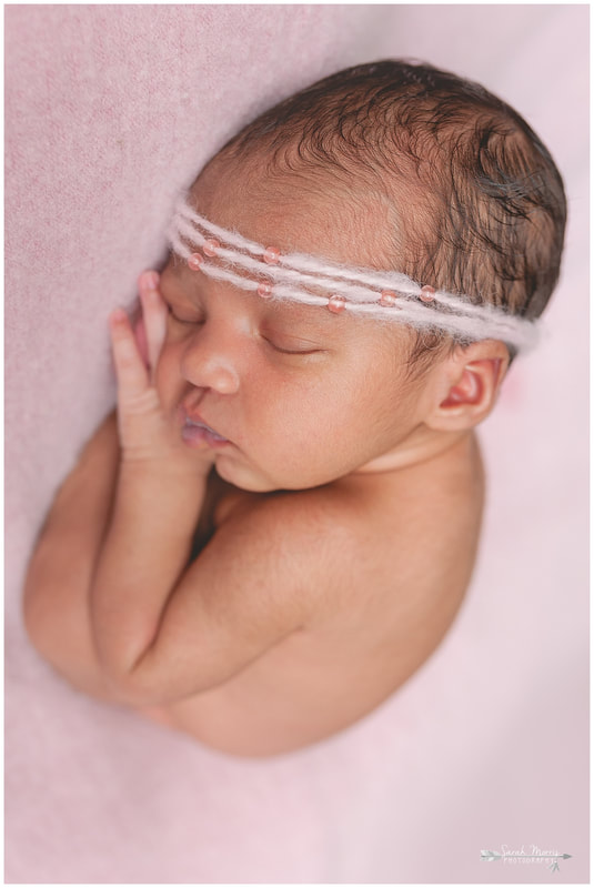 newborn photos of baby girl on pink blanket wearing pink headband