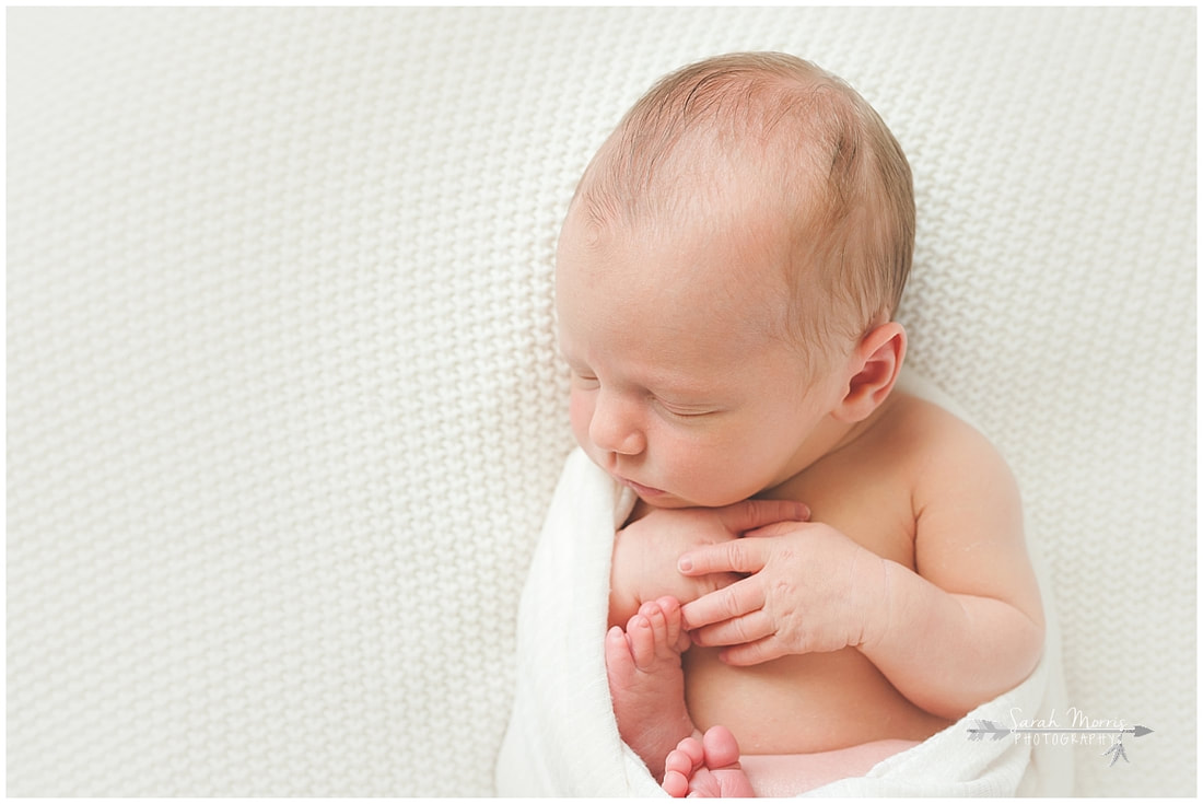 Newborn photo of baby boy sleeping on white blanket