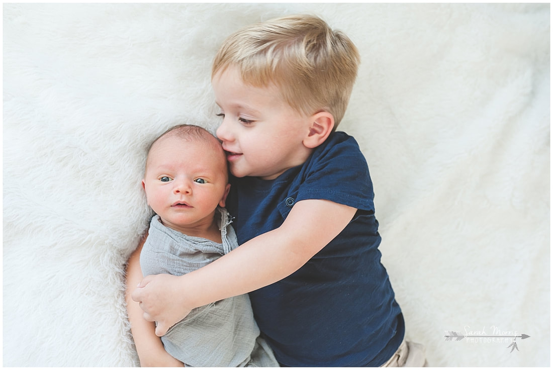 Newborn photos with older siblings on fur rug