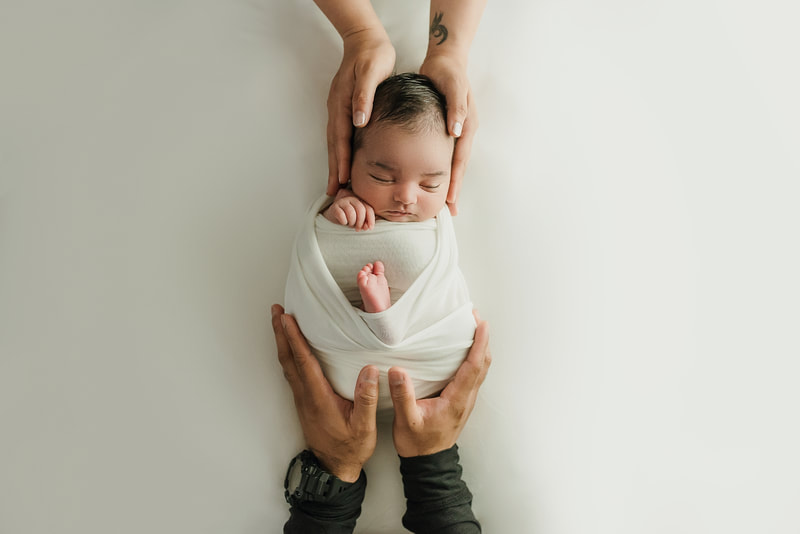 newborn baby girl posed in mom and dad's hands for newborn photo shoot in Memphis, TN