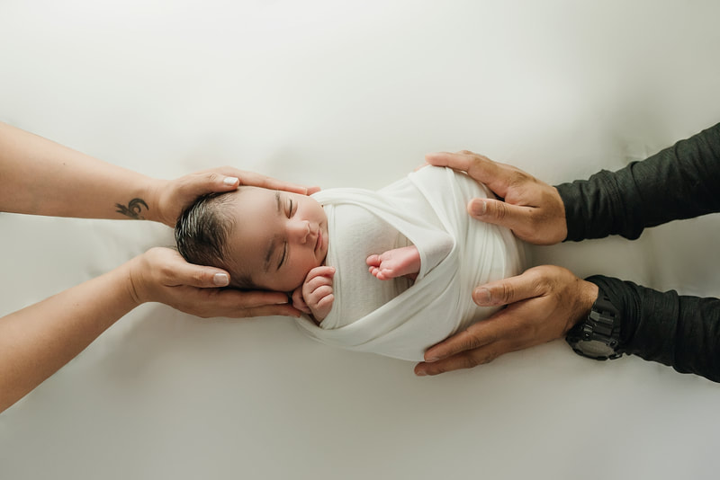 newborn baby girl posed in mom and dad's hands for newborn photo session in Memphis, TN