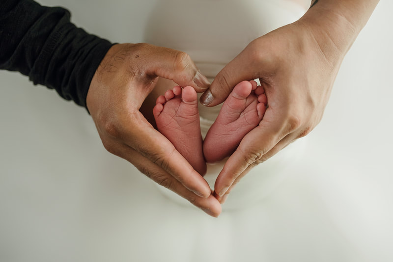 mom and dad making a heart with their hands around newborn baby's feet for newborn photo session in Memphis, TN