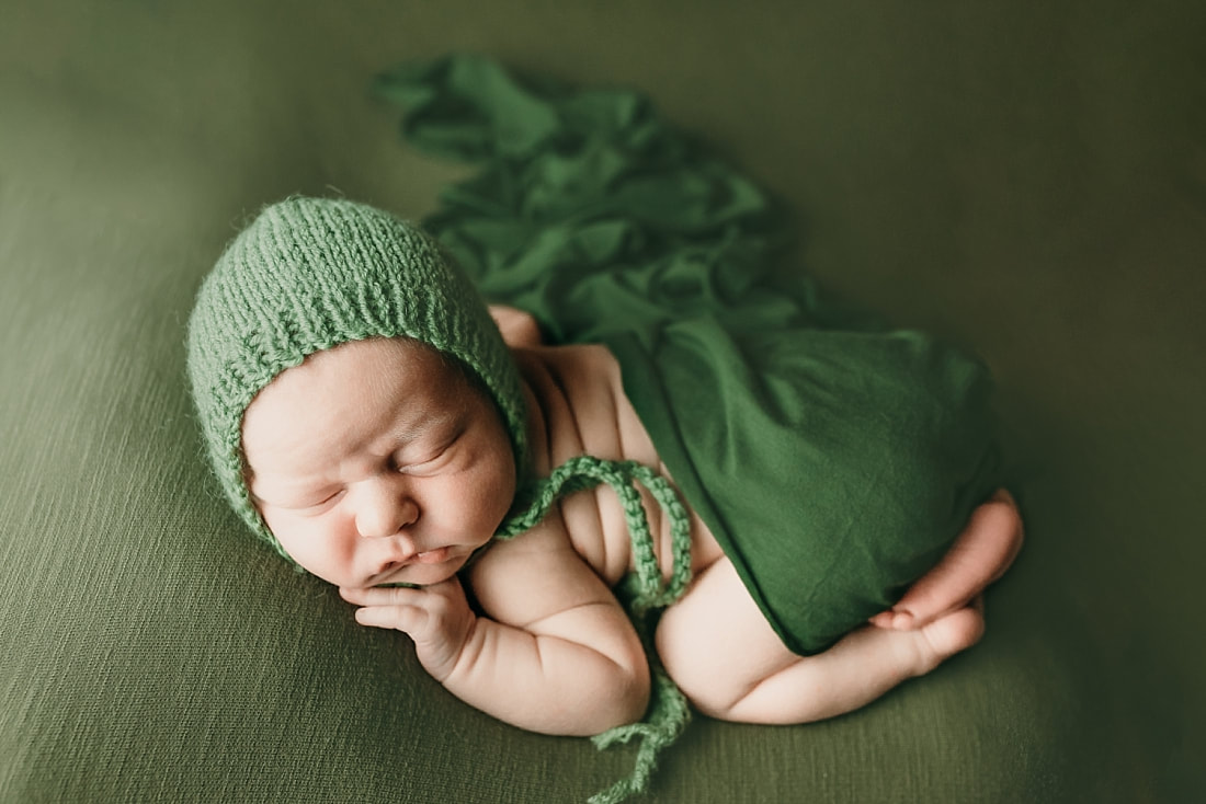 Newborn infant with sweet chubby cheeks sleeping and posed for newborn photos in Memphis, TN
