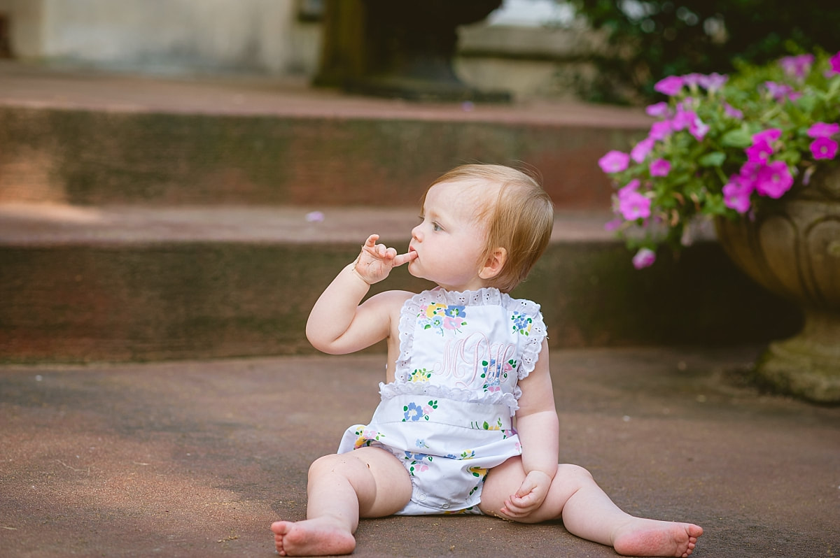 baby girl's first birthday portrait in monogrammed bubble on the front porch during in home lifestyle family session in collierville, tn