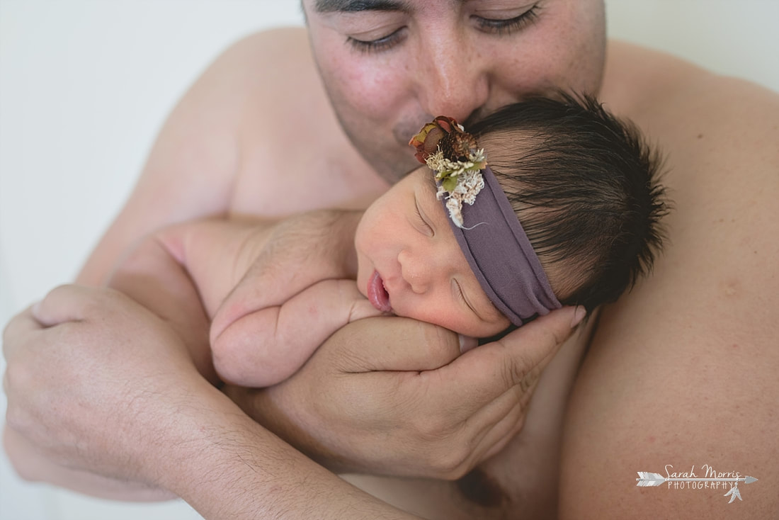 Dad holding new baby girl sking to skin during the lifestyle portion of her newborn photo session