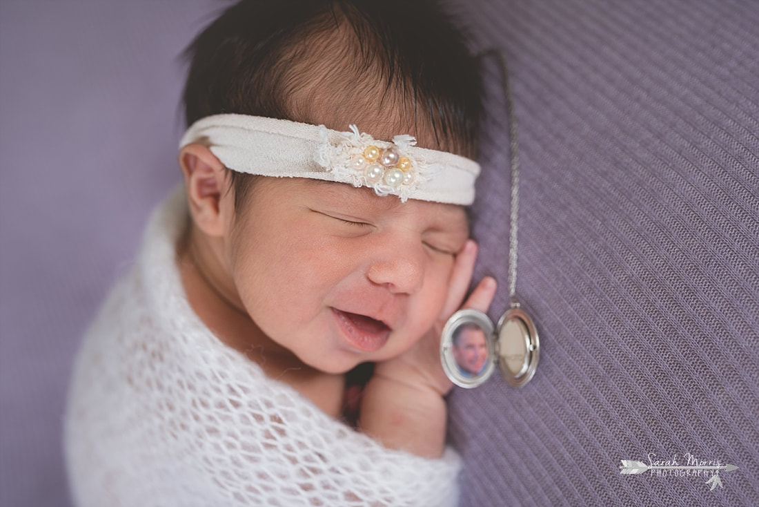 Newborn baby girl wearing a cream headband with pearls and wrapped in a beautiful soft cream knit blanket sleeping on purple blanket during the posed portion of her newborn session