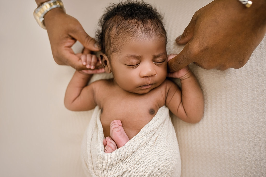 Newborn baby boy holding daddy's hands during newborn photo session in Collierville, TN