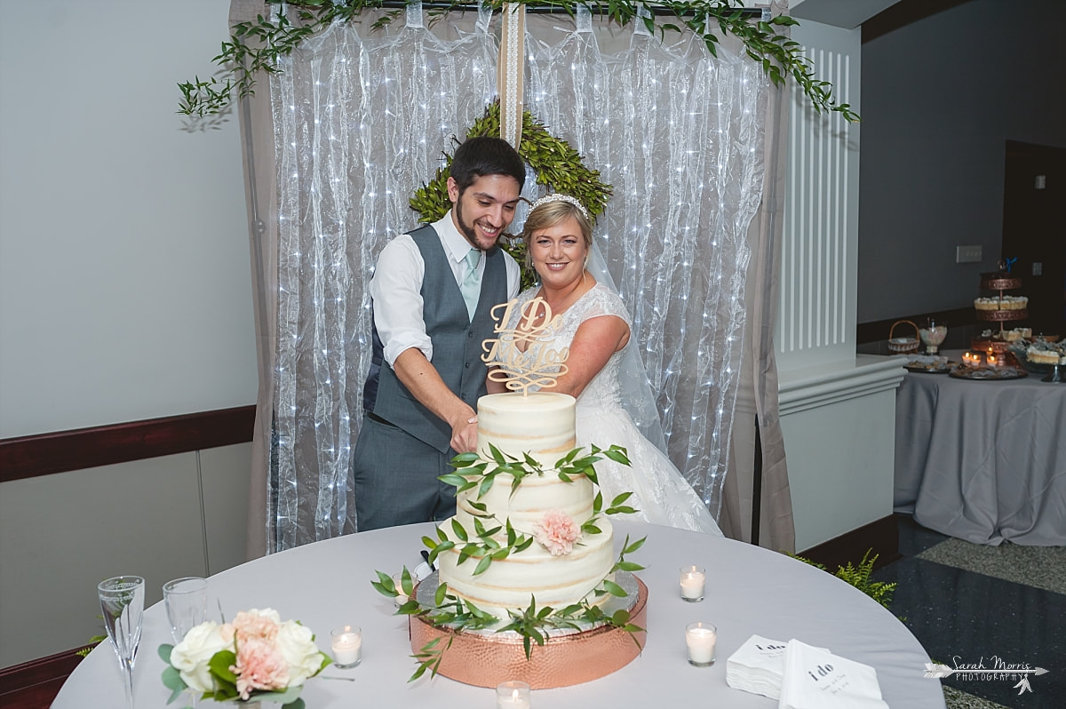 Bride and groom cutting wedding cake made by frost bakery at Annunciation Greek Orthodox Church in Memphis, TN